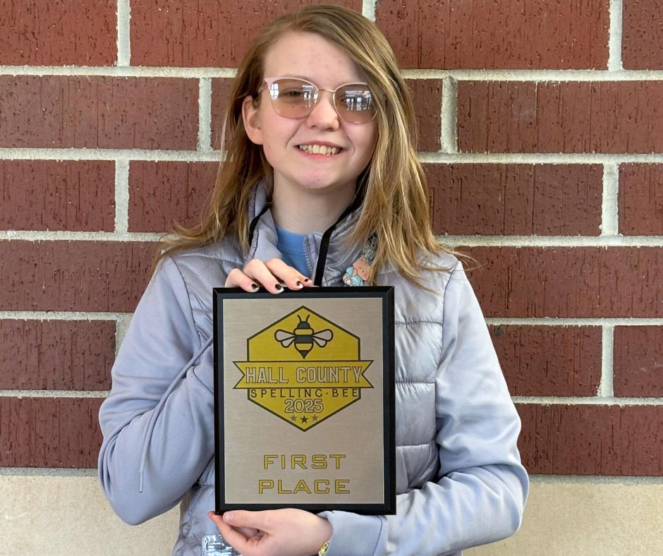 Makenna Ostrander, Westridge 8th Grader, smiling with the Hall County Spelling Bee 1st Place plaque